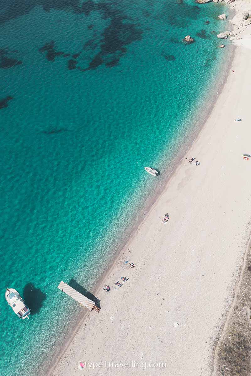 A drone view of a couple of boats anchored in the turquoise water close to the shore of Kroreza Beach.