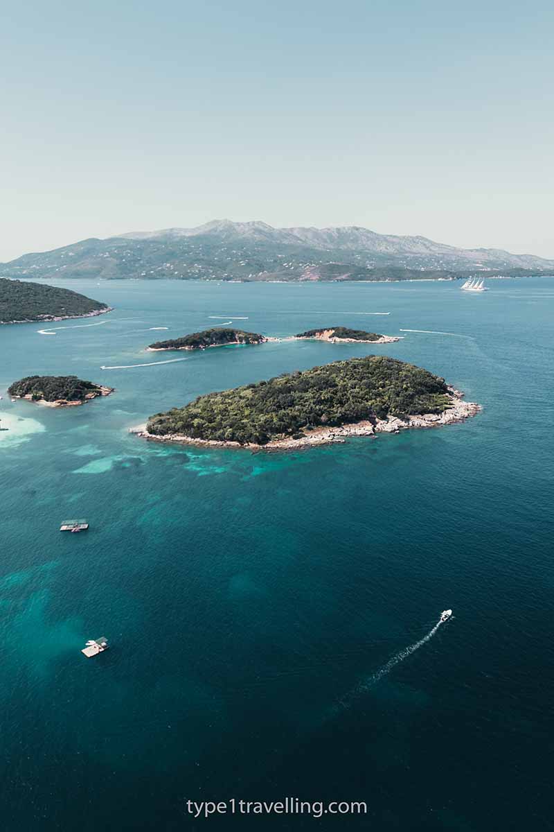 A drone view of the small Ksamil islands with Corfu in the background.