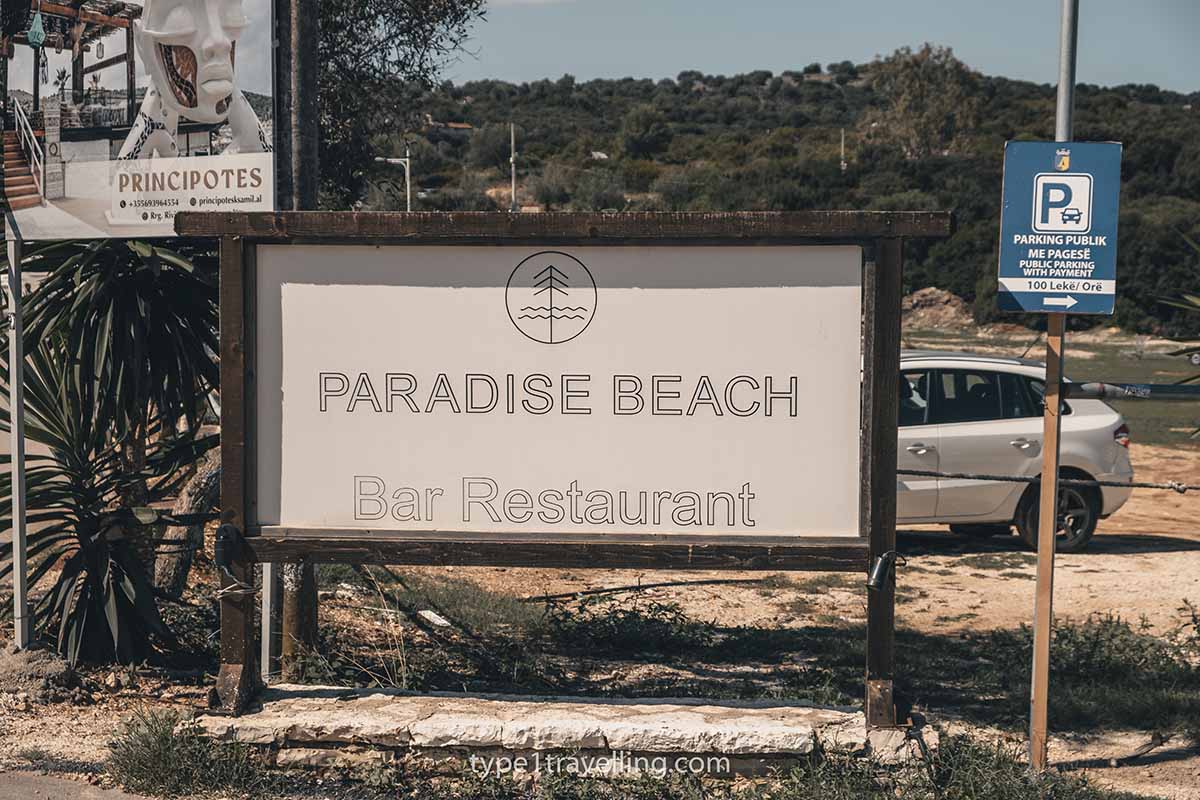 ksamil-parking A large sign for Paradise Beach Bar Restaurant and a smaller sign directing to public parking for 100 lek per hour.