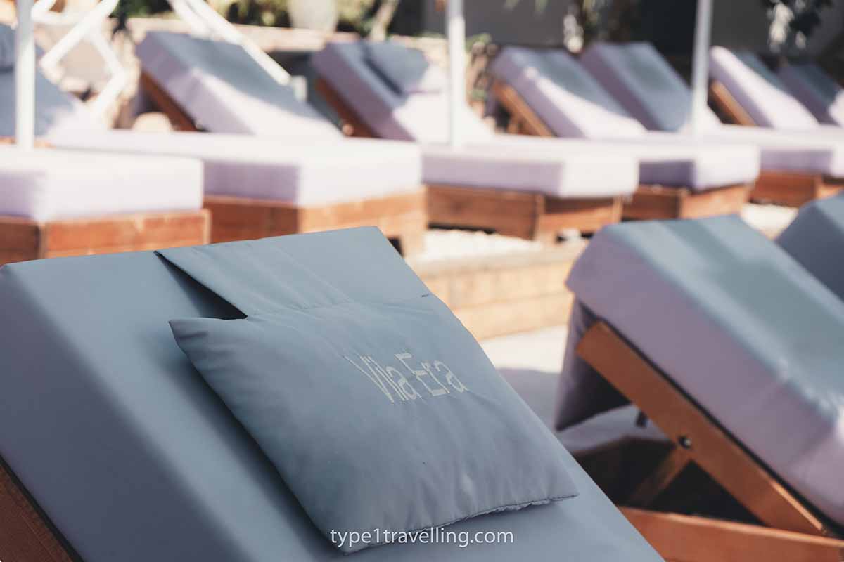 Rows of luxurious sun loungers with pillows that have Vila Era stitched on them.
