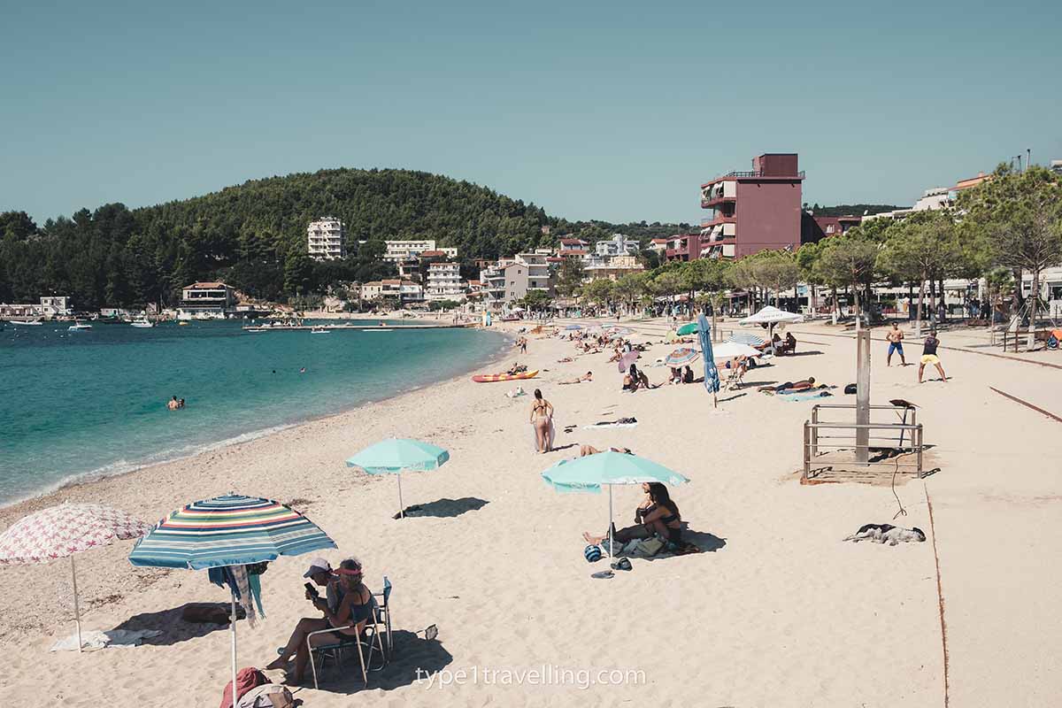 himare-beach Lines of parasols and people sunbathing on Himare Beach.