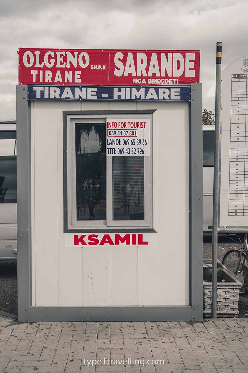 Olgeno Tirane's ticket office which displays signs for Sarande, Tirane - Himare, Ksamil, and phone numbers for tourists to call.