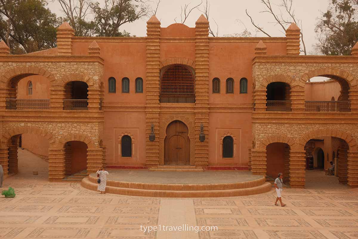 agadir-medina-amphitheatre Two people walking around the open area of the amphitheatre in front of a grand buidling in Agadir Medina.