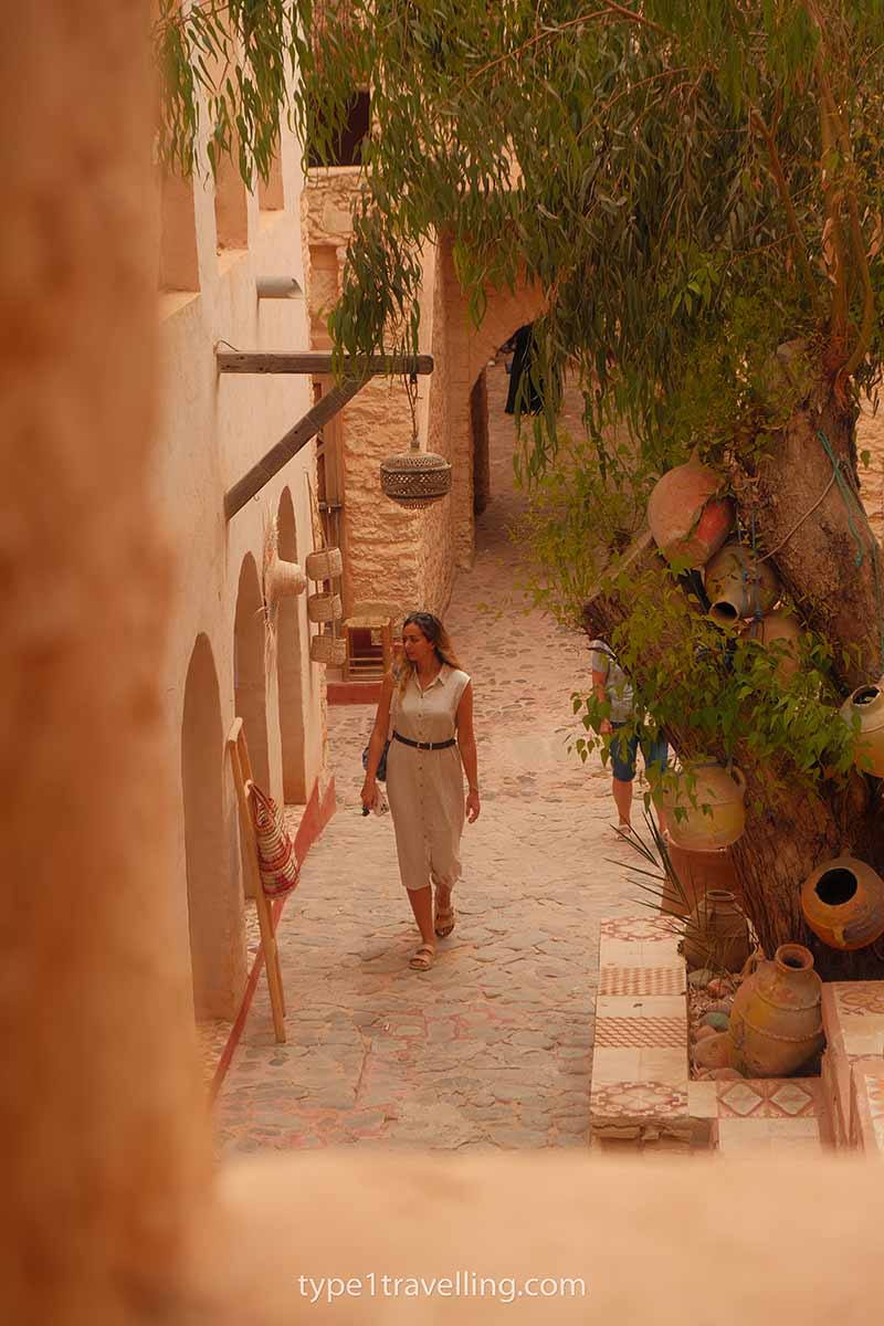 A woman walking along a street in Agadir Medina while looking in the shop windows.