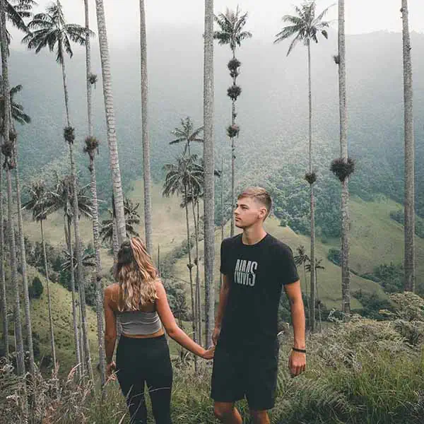 cocora-valley-colombia A couple holding hands surrounded by towering palm trees in Valle de Cocora in Colombia.