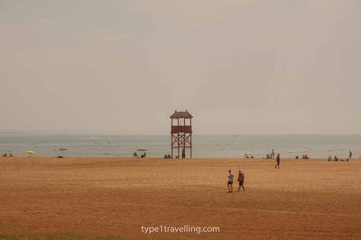 A lifeguard tower and several beachgoers on the golden sands of Agadir Beach which has lots of open space.