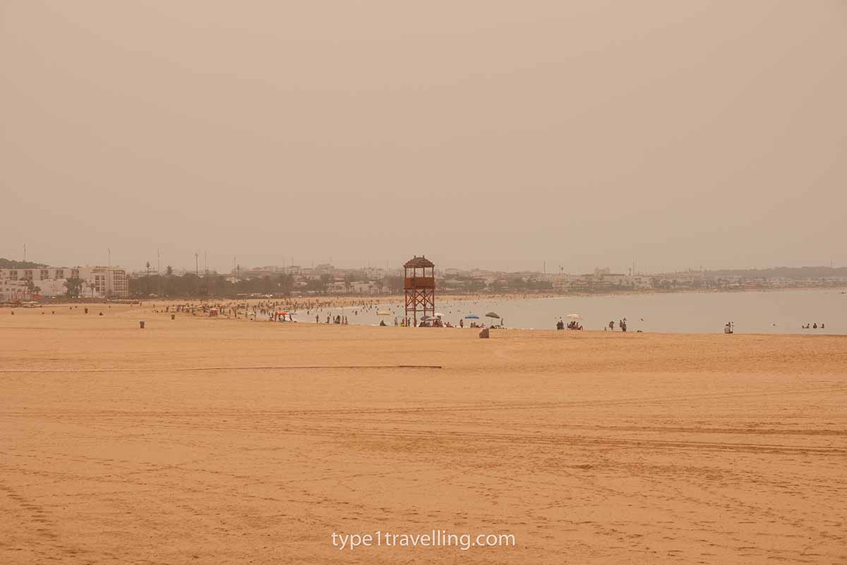 agadir-beach The wide and vast golden sands of Agadir Beach which is mostly empty apart from the beachgoers spread out along the shoreline.