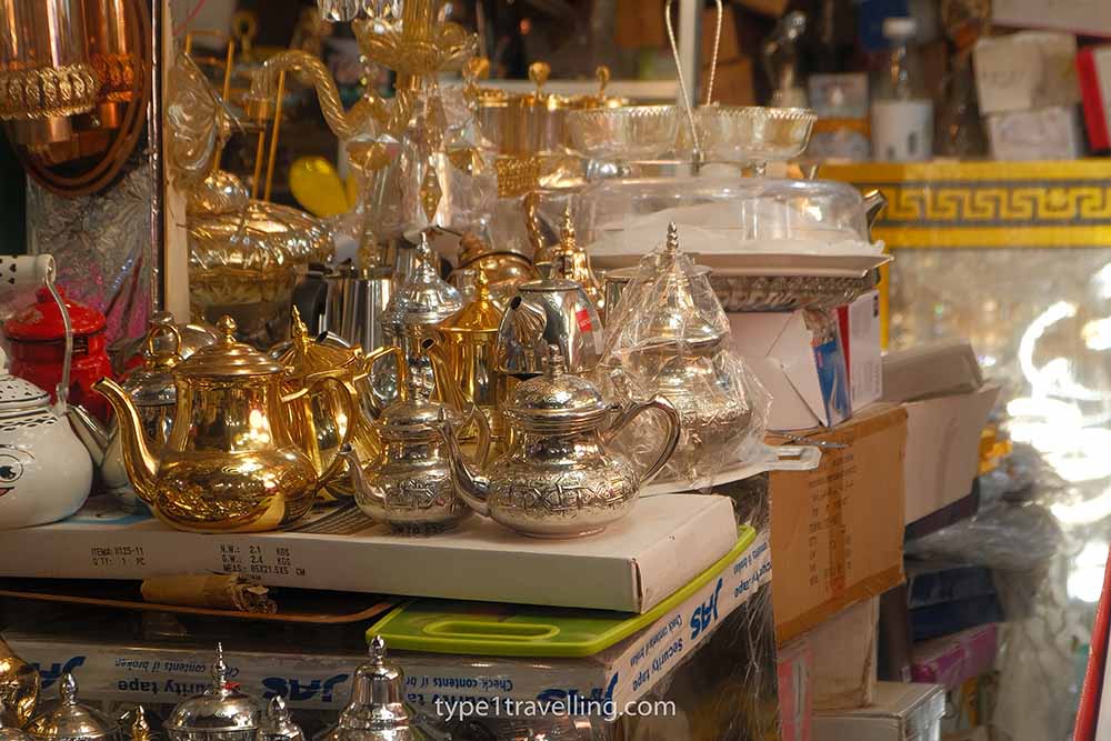 Gold and silver coloured teapots, among other goods, on sale at a market stall in Souk El Had.