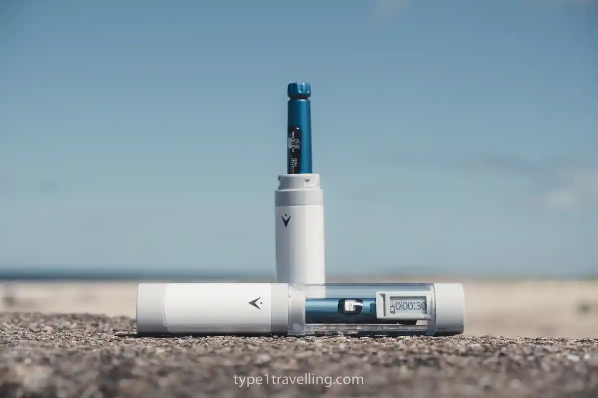 vivi-cap-coolers Two TempraMed VIVI Cap cases with blue insulin pens inserted, resting on a stone surface outdoors.